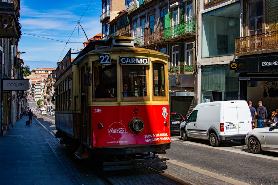 Colorful historic tram on bustling Carmo Street in Porto, showcasing urban life.
